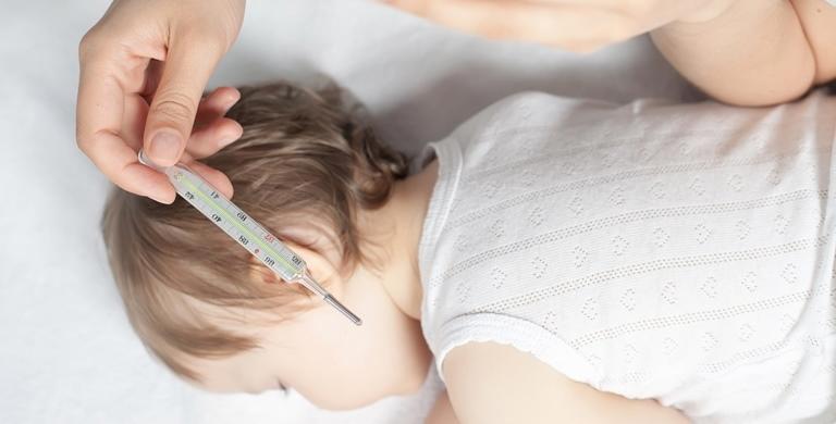 Mother testing temperature of baby with a thermometer