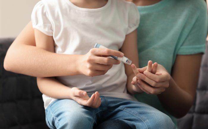 Mother and child pricking thumb for diabetes