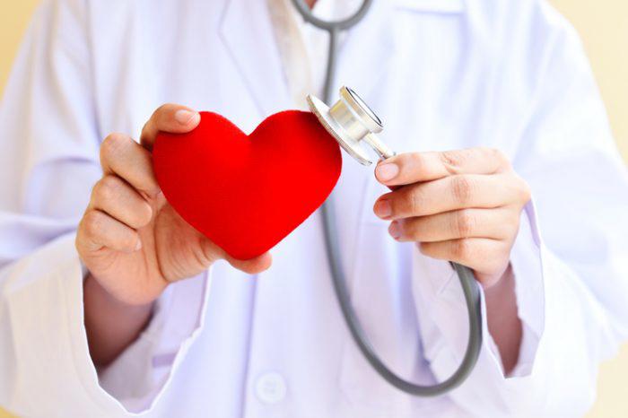 Doctor holding stethoscope to toy heart