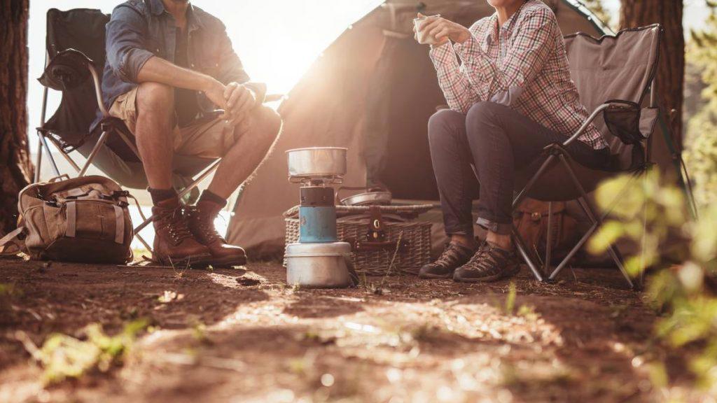 2 people camping in the wilderness enjoying a drink