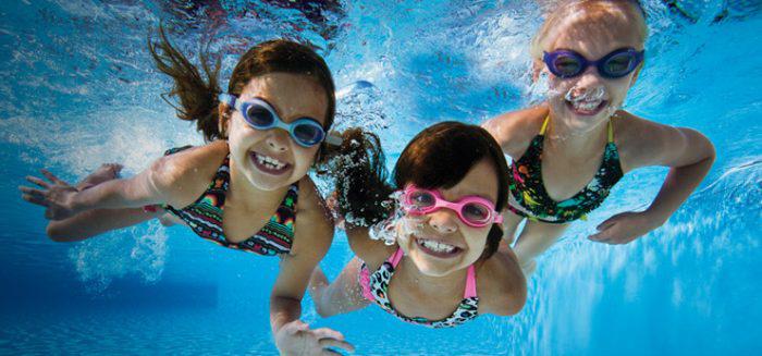 children swimming underwater smiling at the camera