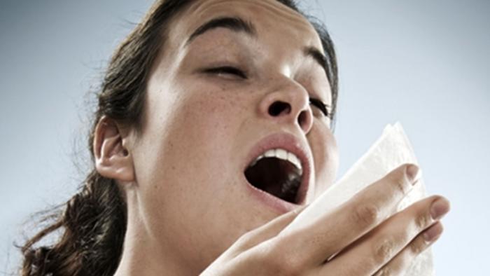 Woman sneezing into tissue