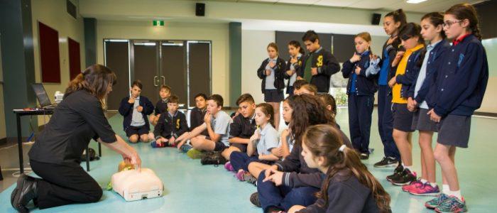 st john trainer showing school children how to perform cpr