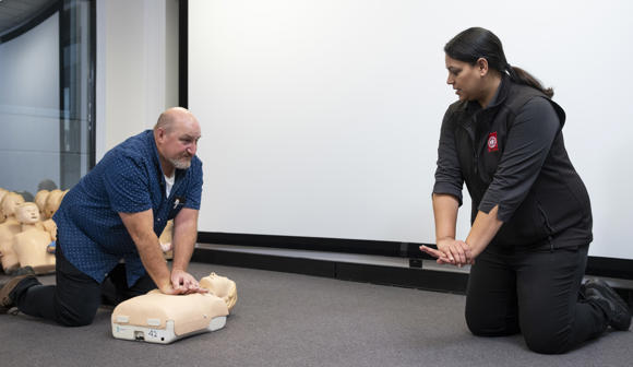 St John first aid training trainer with student on CPR manikin