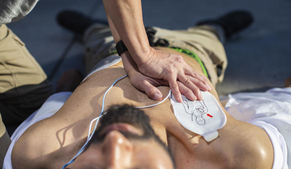 Person performing CPR on a bearded man on the floor