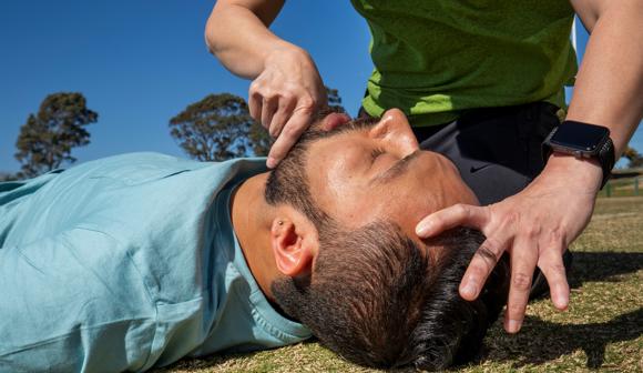 Checking for breathing and objects in mouth of unconscious man