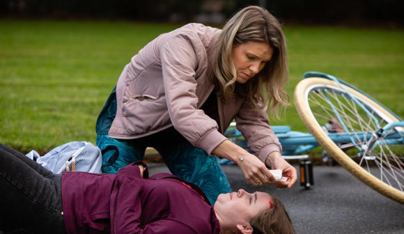 Woman applying first aid to child who fell off bike and hit her head