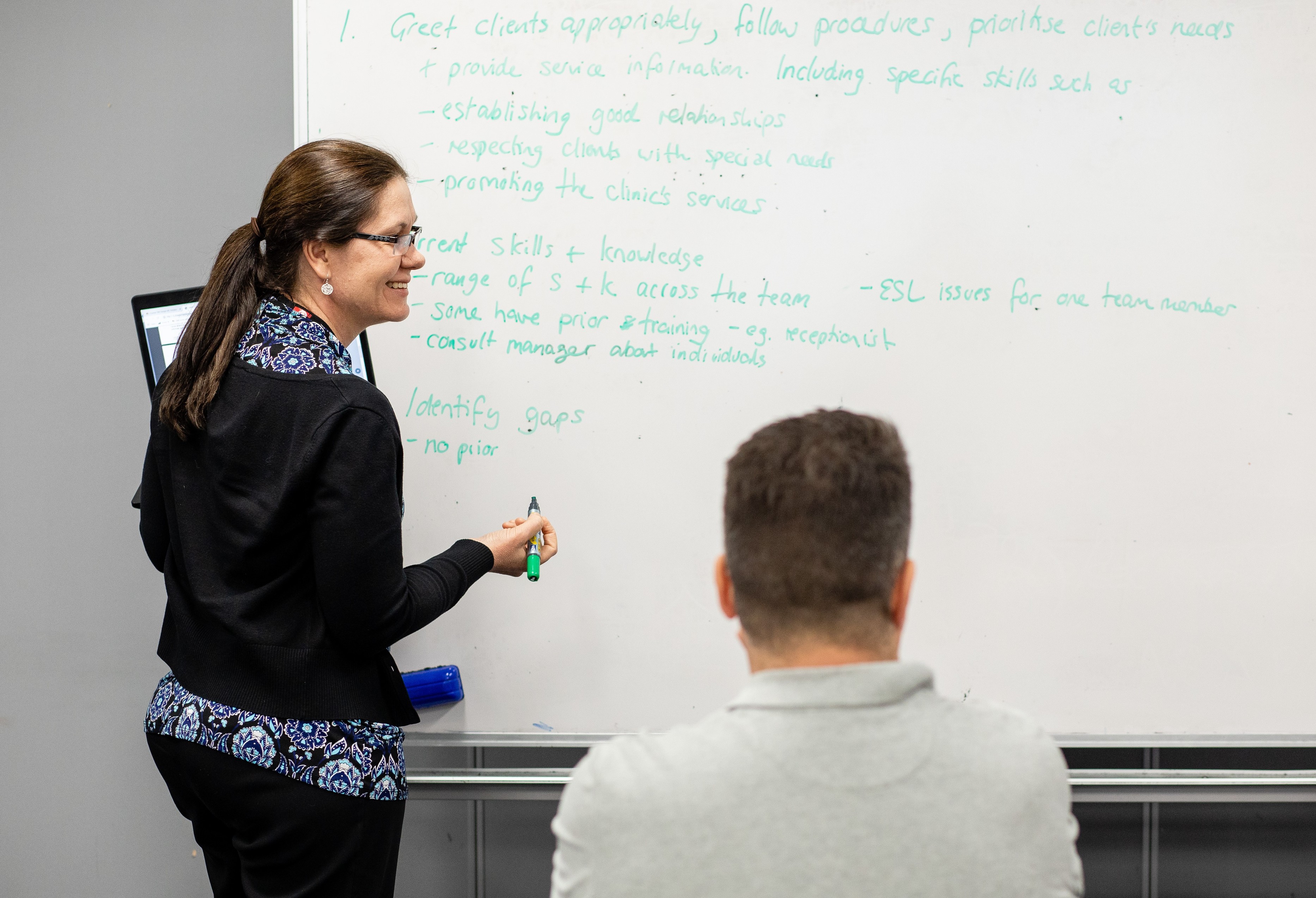 woman writing on class whiteboard