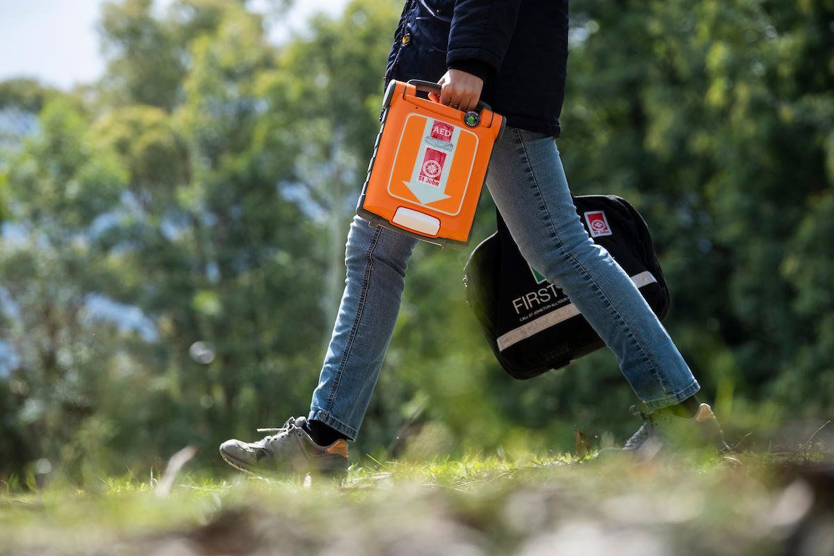 Person carrying Defib and First Aid Kit