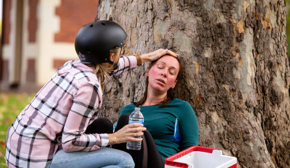 Woman providing first aid to another woman suffering heatstroke