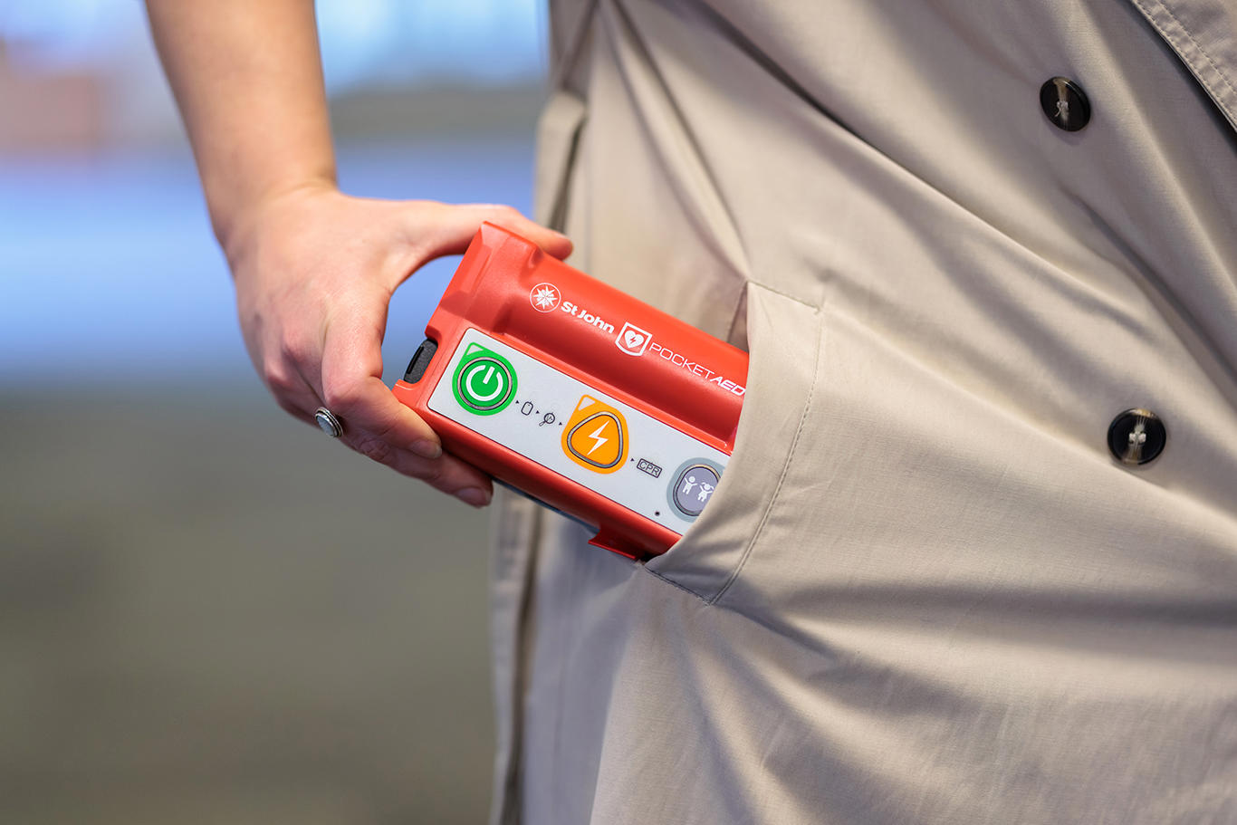 Hand pulling the St John Pocket AED our of a jacket pocket