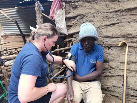 Caitlin helping a local in Tanzania by taking blood pressure